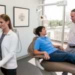 Dr Michael Stewart with young male patient and assistant in his dental office at Stewart & Arango Oral Surgery