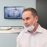 Dr Michael Stewart smiles in his dental offic at Stewart & Arango Oral Surgery